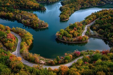 Aerial view of a winding road along a river surrounded by vibrant autumn foliage