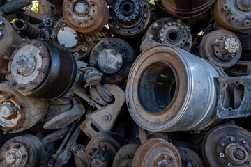 Old rusty truck axles piled in a scrap yard. Discarded heavy truck parts in metal recycling area. Truck axle scrap metal waiting for recycling.