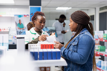 Obraz premium Pharmacy worker delivering professional healthcare advice to a patient near pharmacy shop shelving units, discussing medication and biopharmaceutical options for health improvement.