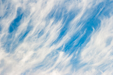 Wispy white clouds drift across a vivid blue sky, creating a serene and expansive natural backdrop. Captures peaceful atmospheric beauty