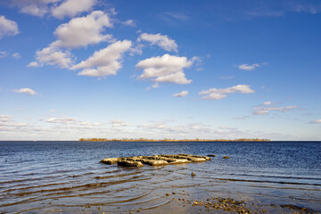 Dnieper River near Cherkasy with calm blue water, a small rocky island and sandy shore under a clear sky with scattered clouds, tranquil landscape and wide open horizon