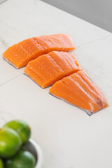 Raw salmon fillets preparing for cooking with fresh lime ingredients on a white marble surface, healthy eating