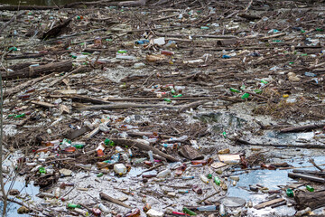 Massive accumulation of plastic bottles, wooden debris, and trash polluting a water body. A stark image of environmental degradation and human neglect
