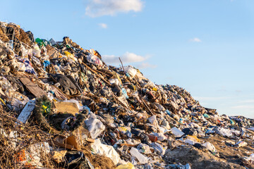 Large landfill site filled with waste materials under a clear blue sky during daylight hours