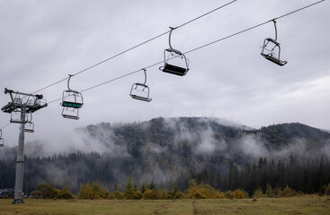 Ski lift without people on the background of mountains, clouds and fog