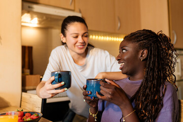 Two women enjoying a joyful morning together, sharing coffee and laughter during a relaxed breakfast in their cozy kitchen