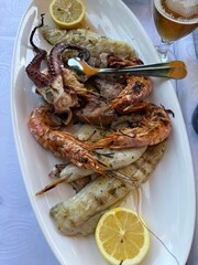 Vertical photo of a Mediterranean seafood platter with grilled shrimp octopus fish and lemon slices taken at a seaside restaurant in Croatia perfect for travel and food stock.