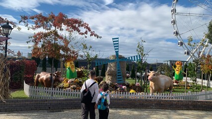  Two boys looking at farm animal sculptures and autumn harvest decorations under a cloudy sky