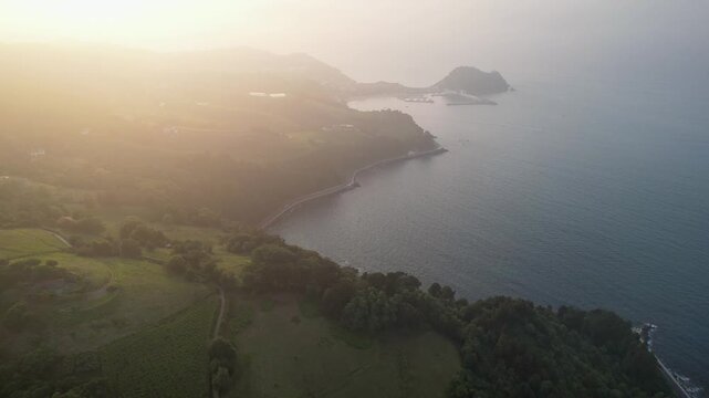 Forward reveal aerial shot of clouds above Zarautz and Getaria at summer sunset. Gipuzkoa, Basque Country, Spain.