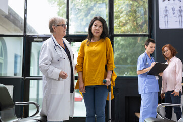 Doctor guiding patient with locomotor disability while using crutches for physical support in...