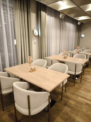 An elegant and spacious restaurant hall with light tables and chairs in a modern style