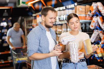 Married couple choose paint brush and paint roller together for their home renovation at a hardware store