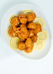 Lemon Chicken on White Plate with Sliced Lemons