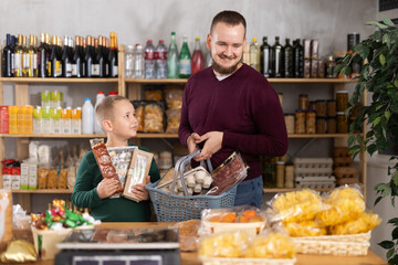Man with a child in a supermarket is choosing groceries. Single father and his son are shopping at a grocery store.
