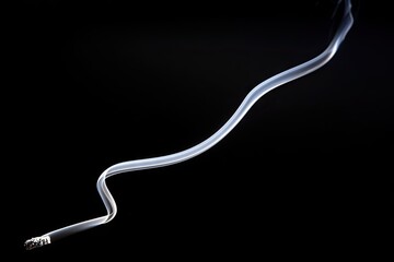 Smoke swirls gracefully upward from a cigarette on black