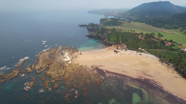 Forward reveal aerial shot of Amio Beach on summer day. Pechon, Cantabria, Spain.
