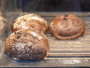 Round rye bread with nuts and raisins in boxes on the counter in the store.