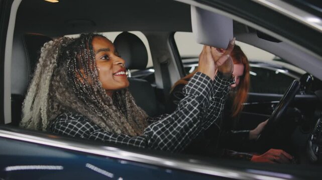 Inside a sleek car, two women explore its interior while a male salesman explains the vehicle s features, creating an engaging moment in a modern dealership - Powered by Adobe