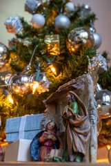Vertical shot of Christmas nativity scene with Mary, Joseph, and Baby Jesus . Christmas tree illuminated in the background