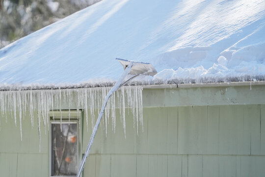 removing snow and icicle on the roof after snow storm