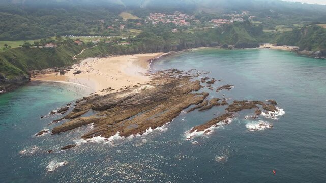 Orbital aerial shot of Amio Beach on sunny summer day. Pechon, Cantabria, Spain.