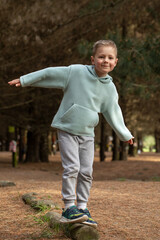 Happy boy balancing on a log during an autumn forest adventure.