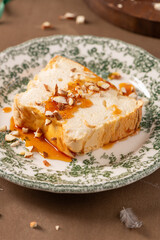 A detailed close-up features a slice of traditional caramelized egg white pudding known as molotof or molotov, generously drizzled with sweet caramel syrup and sprinkled with almond pieces