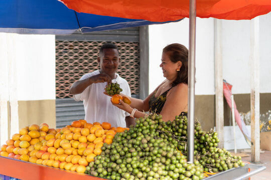 Street vendor selling fresh mamoncillo and tangerines to a customer
