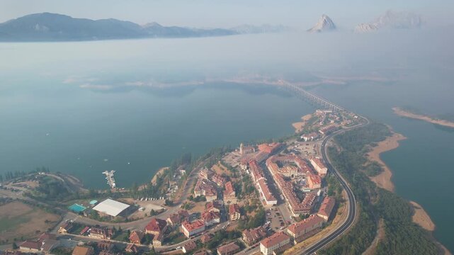 Rising up aerial shot of Ria&ntilde;o town and reservoir under the smoke from forest fires. Castile and Leon, Spain.