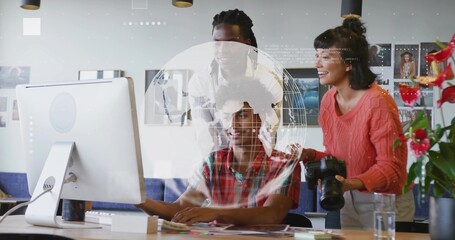 Collaborating colleagues examining data on desktop monitor with digital globe overlay in office
