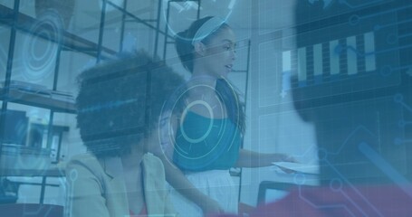 Presenting woman in teal top and white skirt showing holographic charts at office desk, with laptop