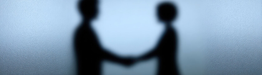 Business handshake silhouette through frosted glass concept showing cooperation and agreement in blurred style