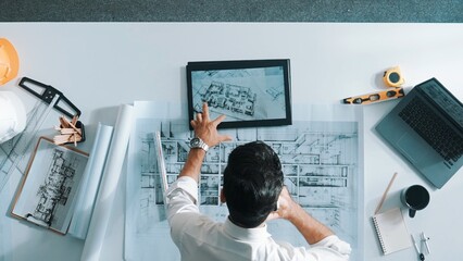 Top down view of skilled engineer talking to manager by using mobile phone while raised hand to...
