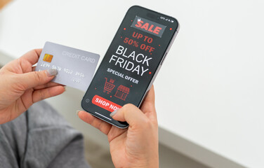 Person using app shop online holding smartphone with Black Friday sale ad and credit card ready for online payment, e-commerce promotions, digital marketing, online shopping and mobile transactions
