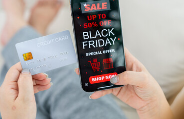 Person using app shop online holding smartphone with Black Friday sale ad and credit card ready for online payment, e-commerce promotions, digital marketing, online shopping and mobile transactions