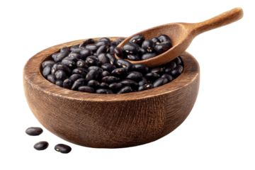 Wooden bowl overflowing with black beans, a wooden spoon nestled within