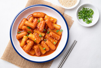Korean Tteokbokki (simmered rice cake) and sausage with spicy sauce on white background, Top view