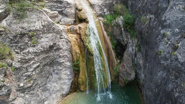 Backward reveal aerial shot of La Gorguina waterfall in Gorg Gorge on summer day. La Febr&oacute;, Tarragona, Spain.