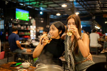 Asian women friends drinking beer at bar