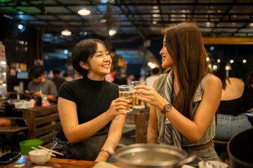 Women friends cheering beer at night restaurant