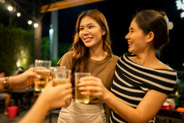 Friends toasting beer glasses enjoying night party