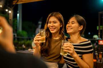 Two happy women enjoying drinks at night party
