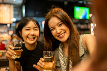 Happy young women friends taking selfie drinking beer