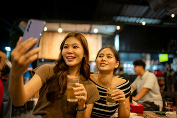 Young women taking selfie, enjoying night out with drinks