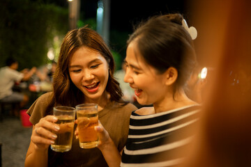 Women friends cheering beer glasses enjoying night out