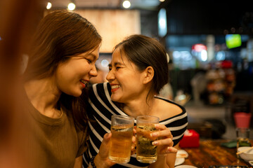 Women friends laughing together toasting drinks at bar