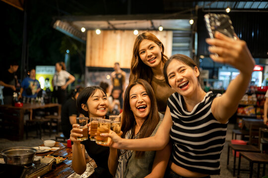 Young asian women friends drinking toasting taking selfie - Powered by Adobe