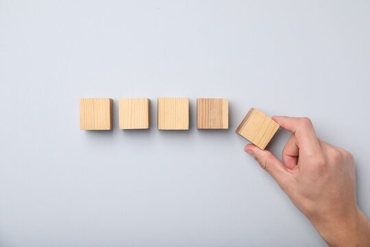 Man with wooden cubes on light background, top view