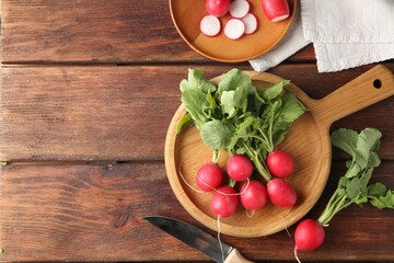 Fresh ripe radishes and knife on wooden table, flat lay. Space for text