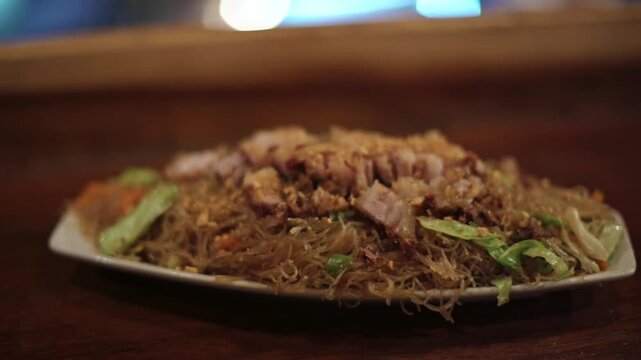 Traditional pancit bihon with meat and vegetables served in Bohol, Philippines, in a rustic food setting